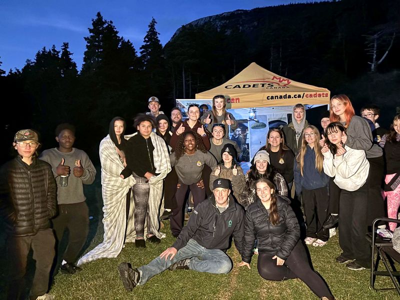 A large group of 166 Fort Townshend cadets and staff in front of the Cadets tent at night